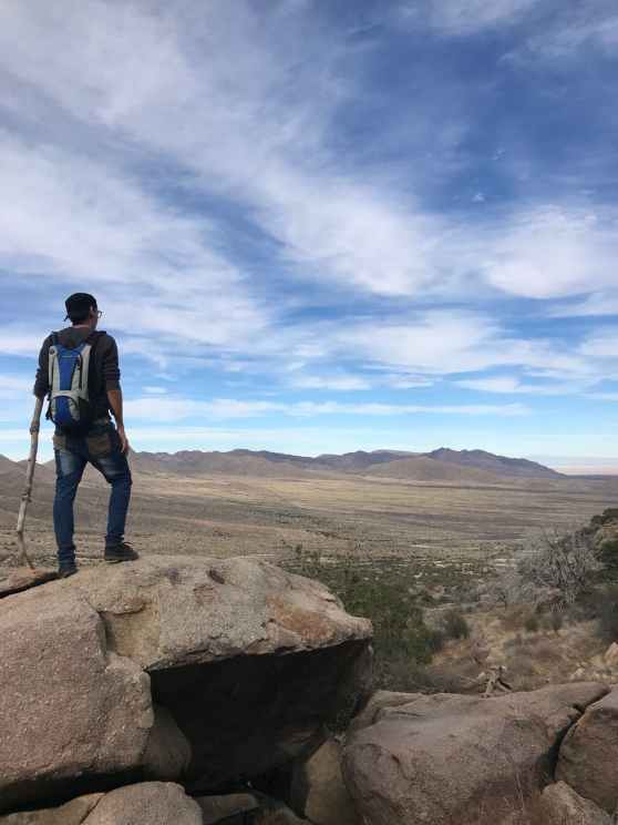 man wearing backpack standing on stone
